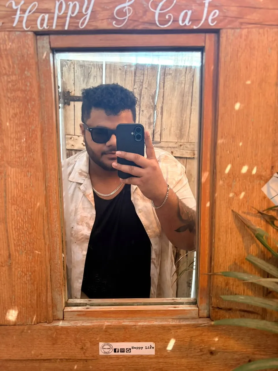 Mirror selfie of Amritash in a café with a wooden frame