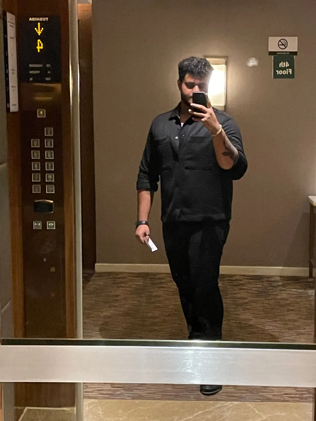 Mirror selfie of Amritash dressed in black inside a lift