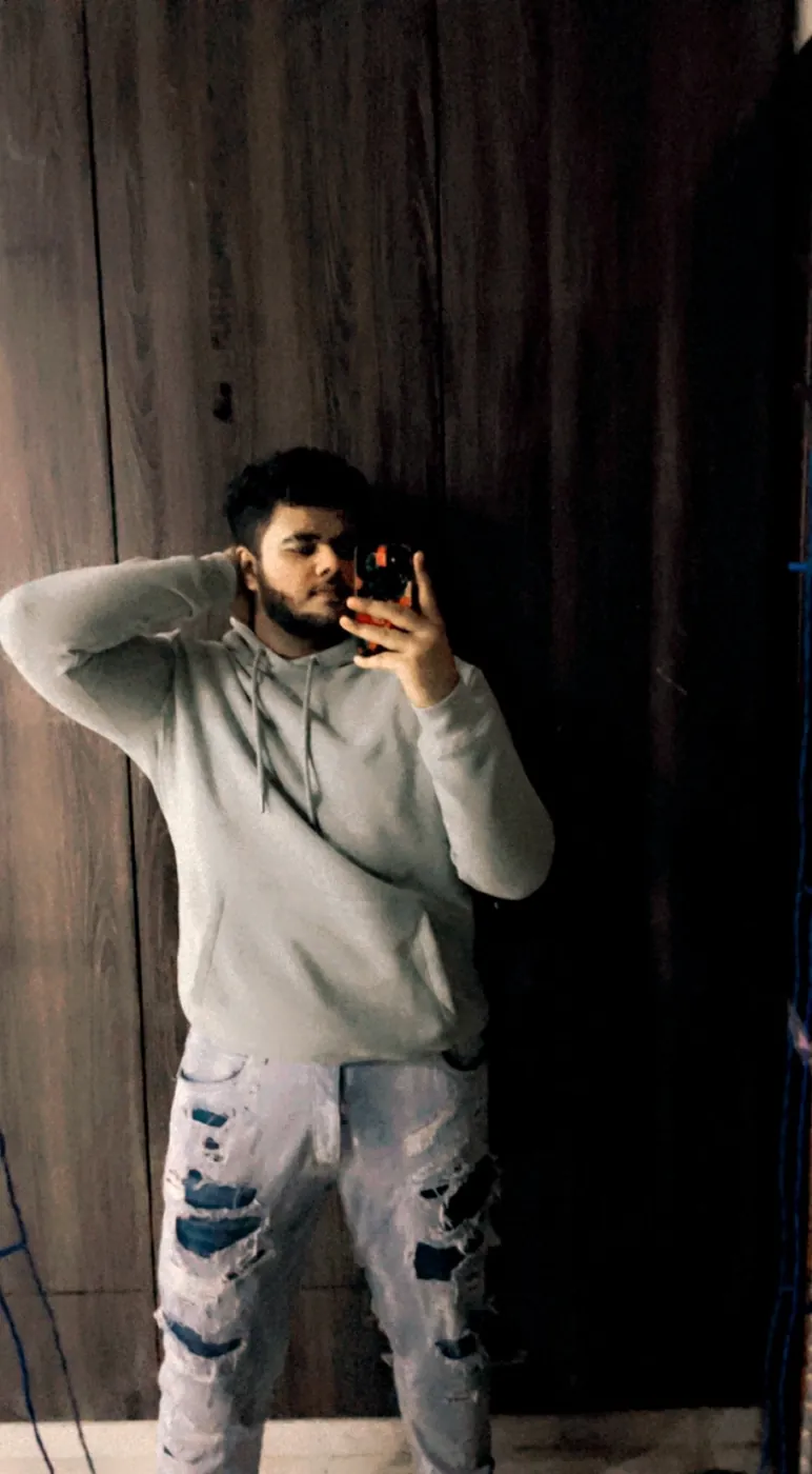 Mirror selfie of Amritash in a grey hoodie and ripped jeans
