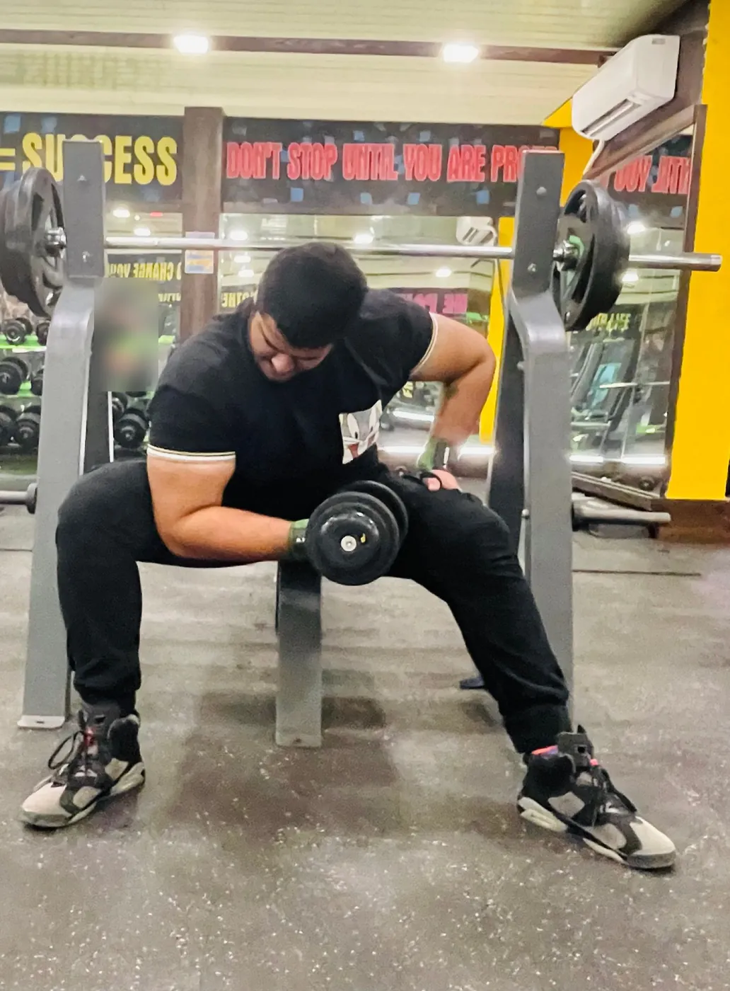 Amritash doing a seated dumbbell curl on a gym bench