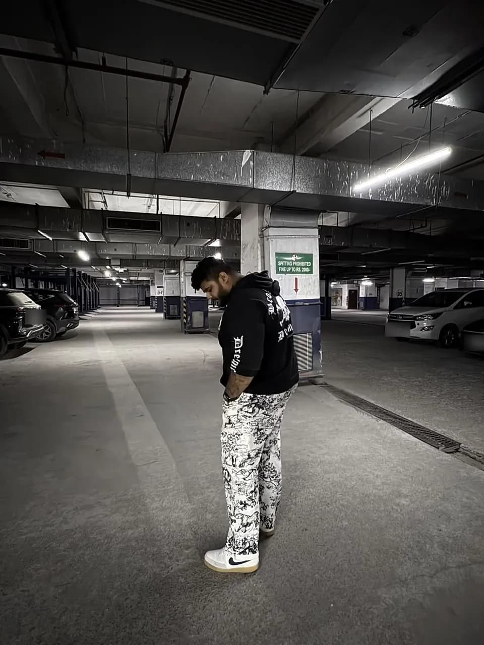 Amritash in a black hoodie and printed trousers in a parking garage