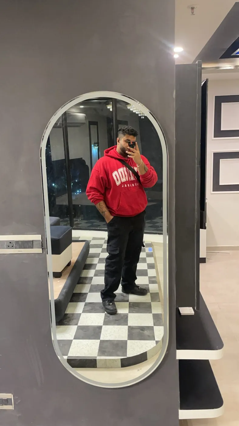 Mirror selfie of Amritash in a red hoodie on a chequered floor
